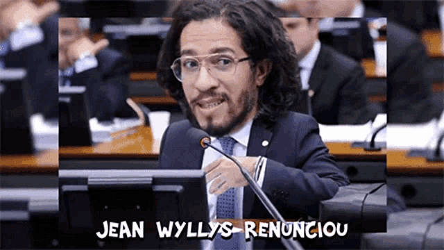 a man in a suit and tie is speaking into a microphone with the words jean wyllys renunciou written above him