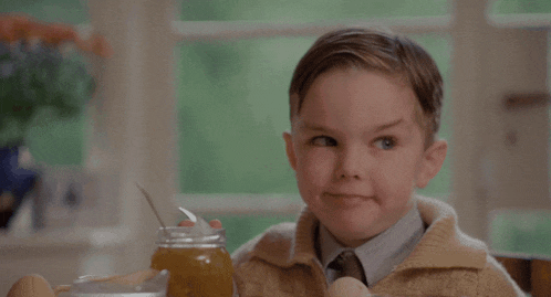 a young boy is sitting at a table with a jar of honey and eggs