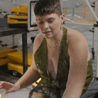 a woman in a green tank top is sitting on the floor in a factory .