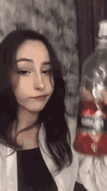 a young woman is holding a bottle of soda in her hand .