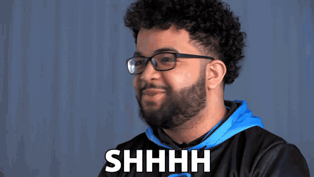 a man with glasses and a beard says " shhhh "