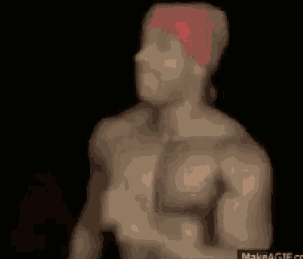 a shirtless man with a red bandana on his head is standing in the dark .