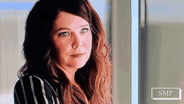 a woman in a striped shirt is looking out a window .