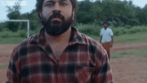 a man in a plaid shirt looks at the camera
