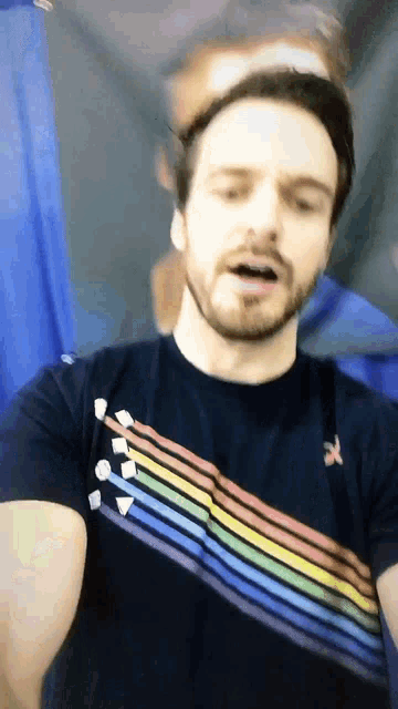 a man with a beard is wearing a black shirt with a rainbow design on it