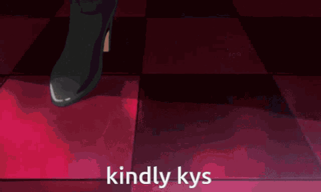 a man in a suit is standing in front of a couch with the words kindly kys written on the floor .
