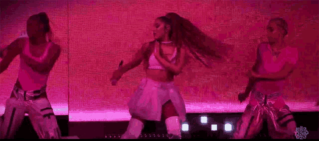 ariana grande is performing on stage with her dancers in pink outfits
