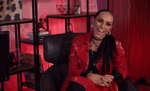 a woman wearing a red jacket is sitting in a chair