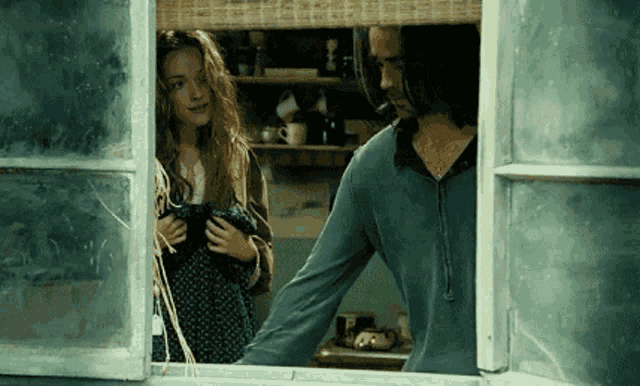 a man and a woman are looking out of a window together