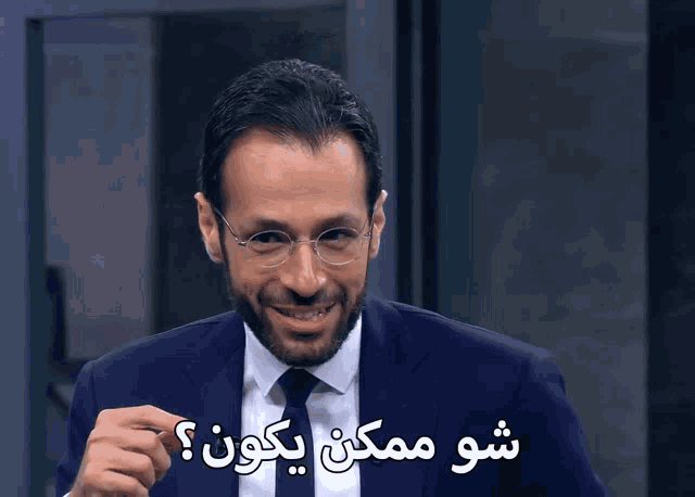 a man wearing glasses and a suit is talking in a foreign language