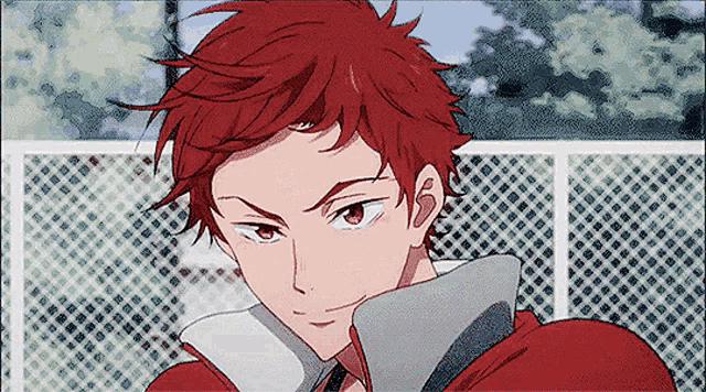 a man with red hair is standing in front of a chain link fence