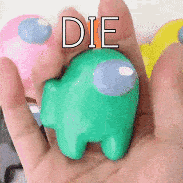 a person is holding a green among us toy in their hand and says die