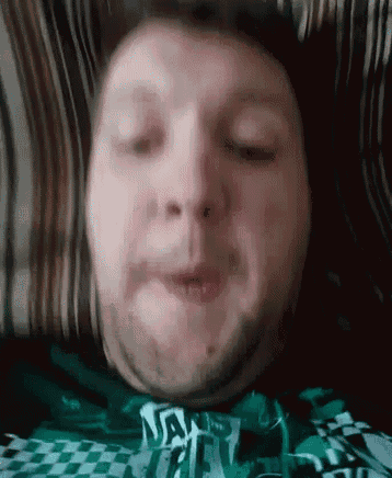 a man with a beard wearing a green shirt that says vans on it