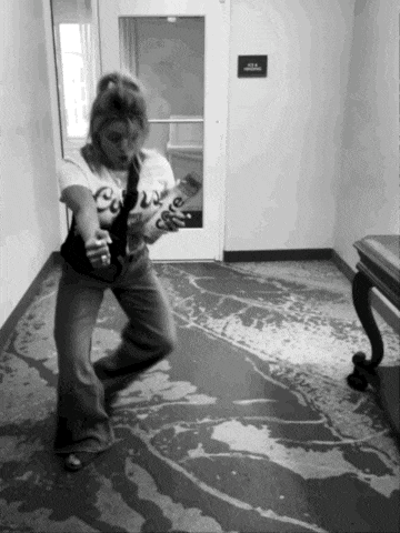 a black and white photo of a woman playing a guitar in a hallway with a sign on the wall that says 924