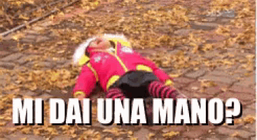 a baby is laying on a pile of leaves with the words mi dai una mano written above him .