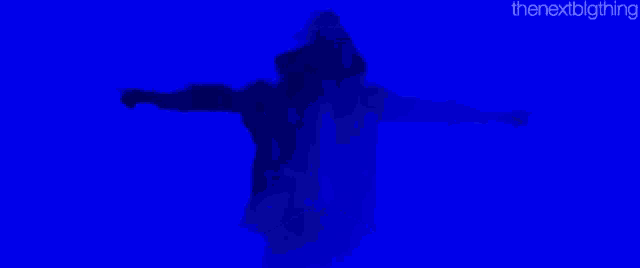 a person with their arms outstretched in front of a blue wall