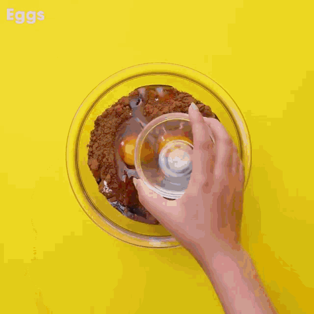 eggs are being poured into a bowl of chocolate