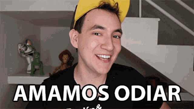 a man wearing a yellow hat and a black shirt with the words amamos odiar on it