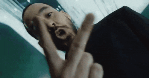 a man with a beard is making a peace sign with his fingers .