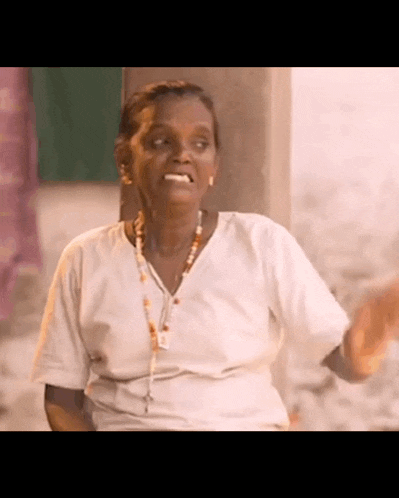 an elderly woman in a white shirt is making a funny face .