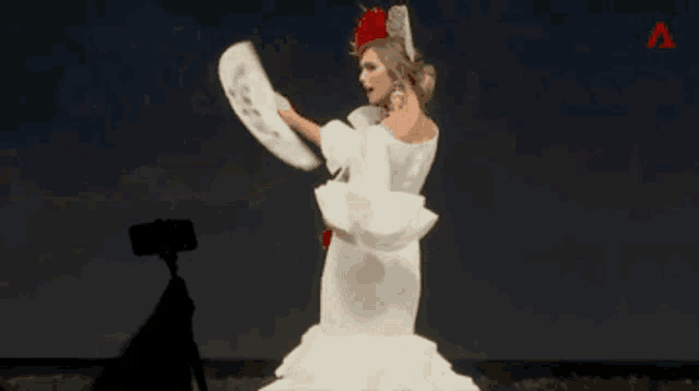 a woman in a white dress is holding a fan in her hand