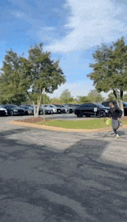 a person is walking in a parking lot with cars parked behind them