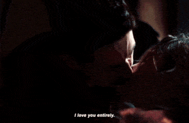 a man in a black shirt says i love you entirely in a dark room