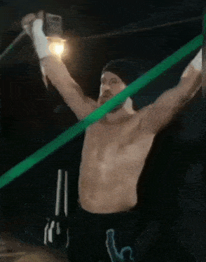 a man without a shirt is holding a green rubber band in his hands .