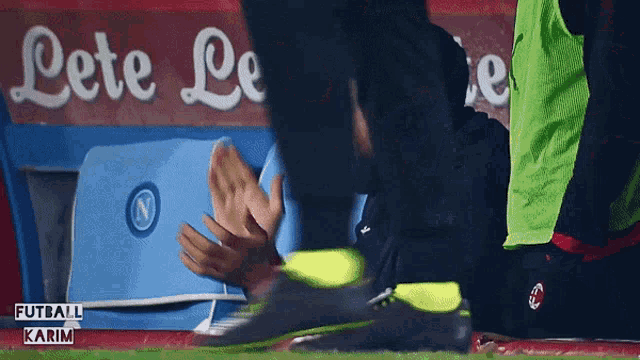 a soccer player is being helped on the field by a person wearing a green vest that says futball karim