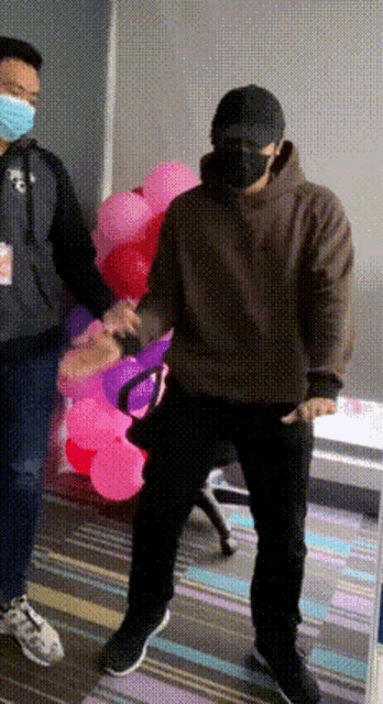 a man wearing a mask is dancing in front of a bunch of balloons