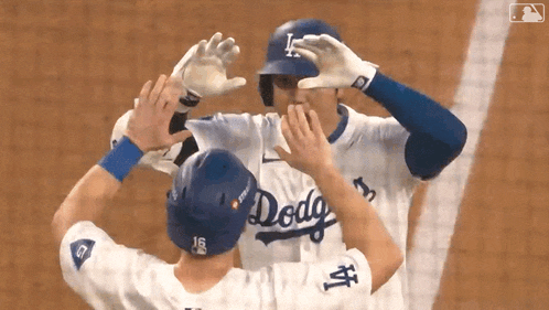 two baseball players wearing dodgers uniforms are hugging
