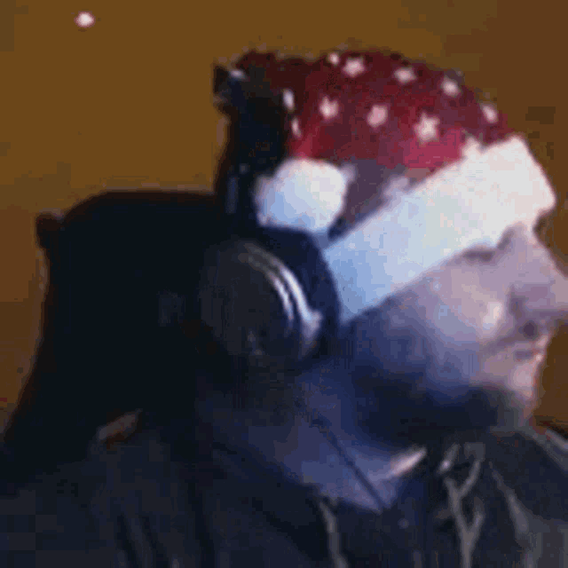 the man is wearing headphones and a santa hat and giving a thumbs up .