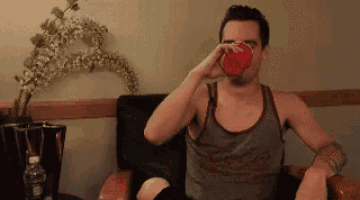 a man sitting in a chair drinking from a red cup .