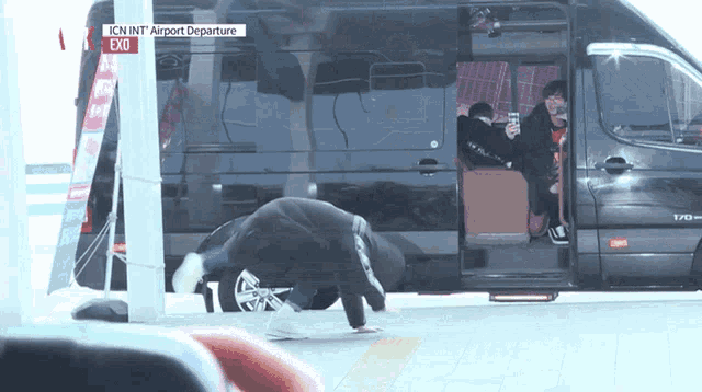 a man kneeling down in front of a van that says exo on the side