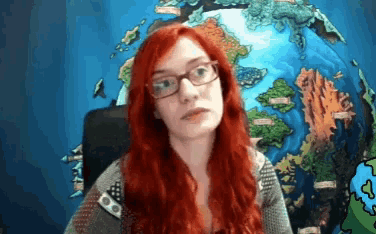 a woman with red hair and glasses is sitting in front of a globe