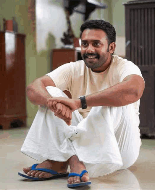 a man sits on the floor wearing flip flops