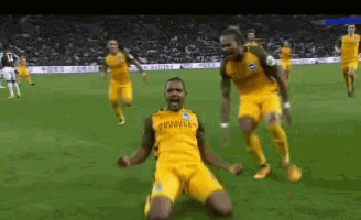 a group of soccer players in yellow uniforms are celebrating a goal on the field