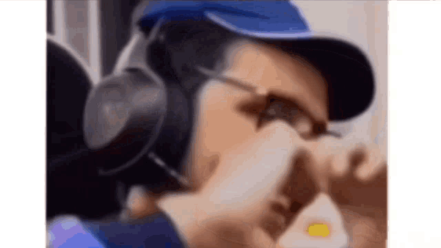 a man wearing headphones and a hat is eating a hamburger .
