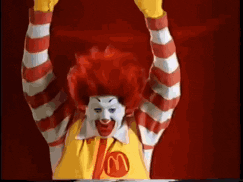 a mcdonald 's clown with red hair and a yellow shirt with a m on it