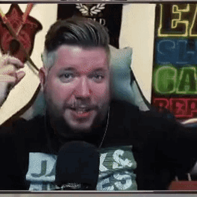 a man with a beard is sitting in front of a microphone in a chair .