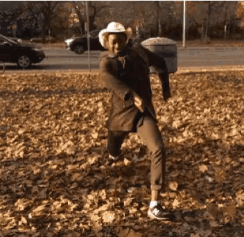 a man in a cowboy hat is dancing in a pile of leaves