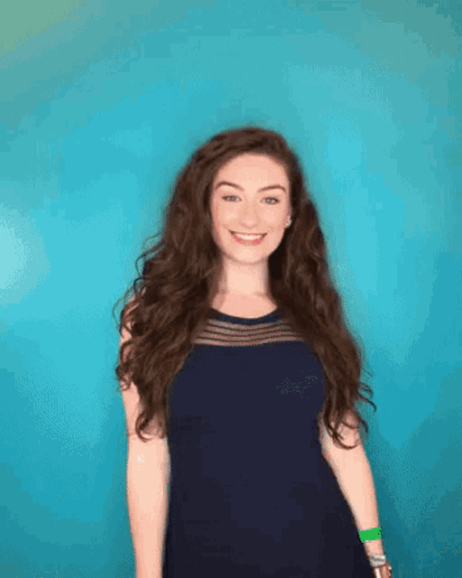 a woman in a blue dress is smiling in front of a blue background
