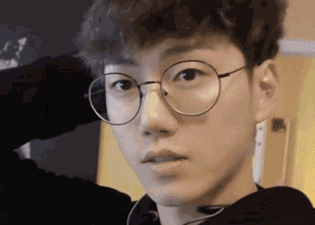 a young man wearing glasses and a black hoodie looks at the camera