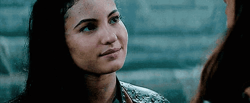 a close up of a woman 's face with a brick wall in the background .