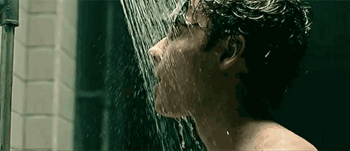 a man is taking a shower with water coming out of his mouth