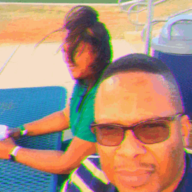 a man wearing sunglasses sits next to a woman at a picnic table