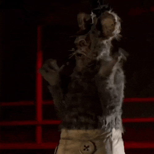 a person in a scarecrow costume is standing in front of a red wall in a dark room .