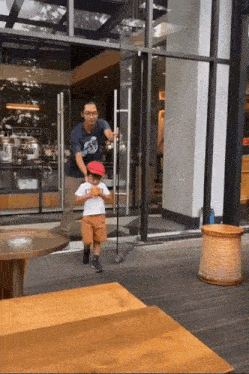 a little boy wearing a red hat and a white shirt is being pushed by a man in a blue shirt