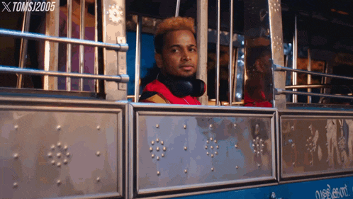 a man wearing headphones looks out the window of a bus with toms / 2005 written on the bottom