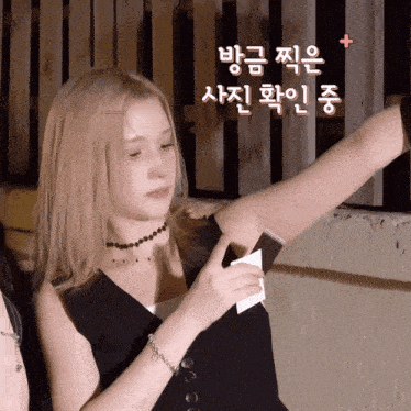 a woman with blonde hair is holding a piece of paper in front of her armpit with korean writing on it